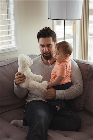 simsearch:700-06758135,k - Father and baby playing with teddy bear on sofa in living room at home Stock Photo - Premium Royalty-Free, Code: 6109-08944705