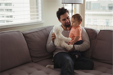 simsearch:700-06758135,k - Father and baby playing with teddy bear on sofa in living room at home Stock Photo - Premium Royalty-Free, Code: 6109-08944706