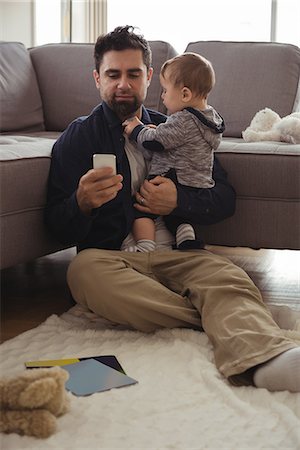 simsearch:6116-07236010,k - Father holding his baby while using mobile phone at home Stock Photo - Premium Royalty-Free, Code: 6109-08944728