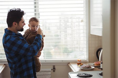 simsearch:6116-07236010,k - Father and his baby using mobile phone in kitchen Stock Photo - Premium Royalty-Free, Code: 6109-08944736
