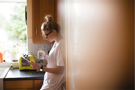 furnished - Woman using digital tablet while having coffee in kitchen at home Stock Photo - Premium Royalty-Free, Code: 6109-08945010