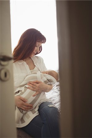 simsearch:6102-08566788,k - Mother breastfeeding baby while sitting on bed at home Stock Photo - Premium Royalty-Free, Code: 6109-08945216