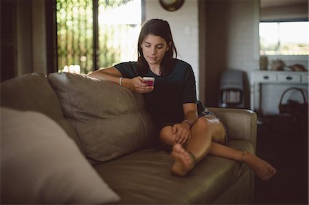 dials - Beautiful woman using mobile phone in living room at home Stock Photo - Premium Royalty-Free, Code: 6109-08945478