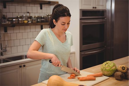 serving gourmet food - Young female chef slicing carrot on counter in professional kitchen Stock Photo - Premium Royalty-Free, Code: 6109-08945434