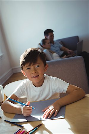 simsearch:6108-06166629,k - Portrait of happy boy drawing in paper while parents using laptop in background Stock Photo - Premium Royalty-Free, Code: 6109-08953077