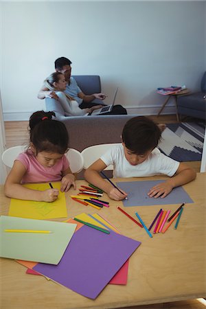 simsearch:6109-07497438,k - Boy and girl drawing in paper while parents using laptop in background Stock Photo - Premium Royalty-Free, Code: 6109-08953075