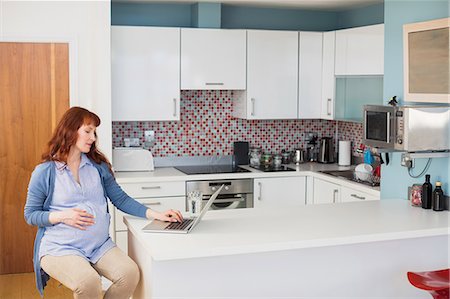 flat - Pregnant woman using laptop in kitchen Stock Photo - Premium Royalty-Free, Code: 6109-08953274