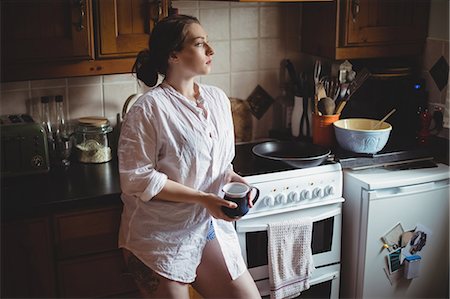 furnished - Thoughtful woman holding coffee cup in kitchen Stock Photo - Premium Royalty-Free, Code: 6109-08953306