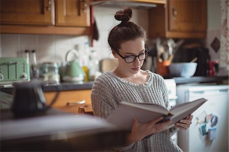 furnished - Woman reading book in kitchen Stock Photo - Premium Royalty-Free, Code: 6109-08953311