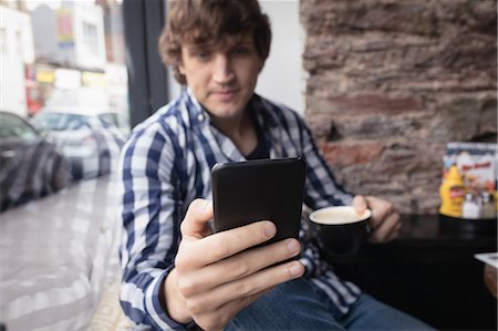 simsearch:6109-08690411,k - Man using mobile phone while having coffee in Café Stock Photo - Premium Royalty-Free, Code: 6109-08953869