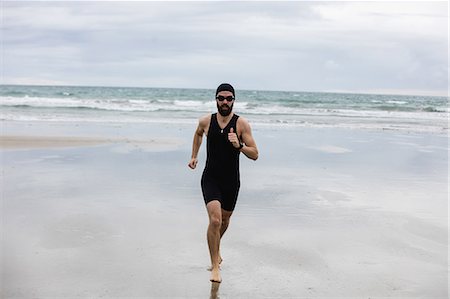simsearch:6109-06003758,k - Man in swimming costume and swimming cap running on beach Stock Photo - Premium Royalty-Free, Code: 6109-08928452