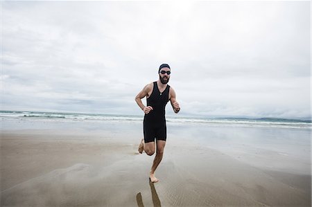 simsearch:628-05817723,k - Man in swimming costume and swimming cap running on beach Stock Photo - Premium Royalty-Free, Code: 6109-08928457