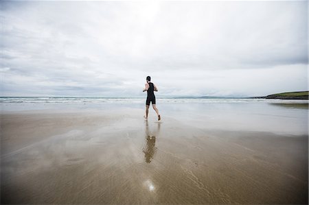 simsearch:400-04535435,k - Rear view of man in swimming costume and swimming cap running on beach Stock Photo - Premium Royalty-Free, Code: 6109-08928458