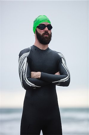 simsearch:6109-06003758,k - Athlete in wet suit standing with his hands crossed on the beach Stock Photo - Premium Royalty-Free, Code: 6109-08928494