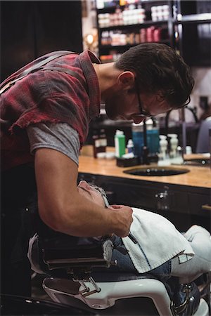 Man getting his beard shaved with razor in barber shop Stock Photo - Premium Royalty-Free, Code: 6109-08928753