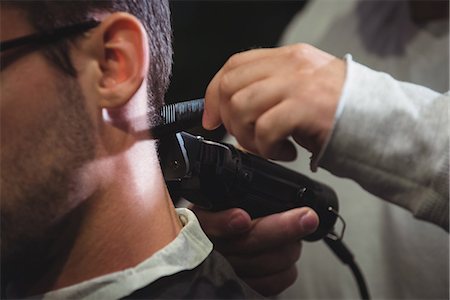 Close-up of man getting his hair trimmed with trimmer in barber shop Photographie de stock - Premium Libres de Droits, Code: 6109-08928810