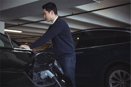 renewal - Man using laptop while charging electric car in garage Stock Photo - Premium Royalty-Free, Code: 6109-08928992