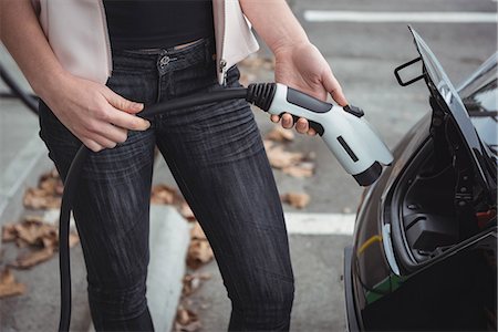 Mid section of woman charging electric car on street Stock Photo - Premium Royalty-Free, Code: 6109-08929042