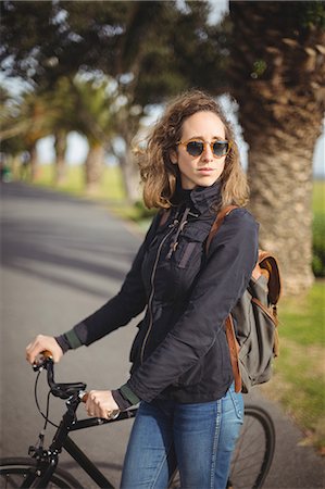 Woman standing with bicycle on the road Stock Photo - Premium Royalty-Free, Code: 6109-08929231