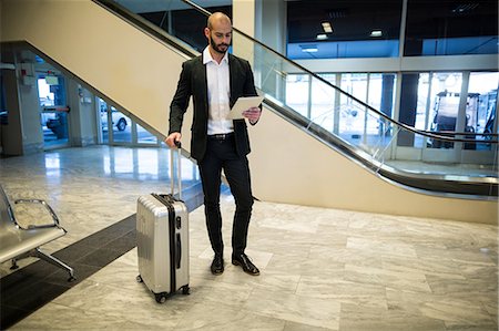 simsearch:400-03938985,k - Businessman standing with luggage using digital tablet in waiting area at airport terminal Foto de stock - Sin royalties Premium, Código: 6109-08929346
