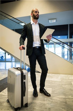 simsearch:400-03938985,k - Businessman standing with luggage using digital tablet in waiting area at airport terminal Foto de stock - Sin royalties Premium, Código: 6109-08929354