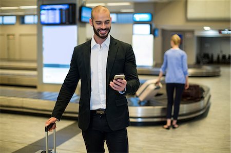 simsearch:400-03938985,k - Businessman standing with luggage using mobile phone in waiting area at airport terminal Foto de stock - Sin royalties Premium, Código: 6109-08929363