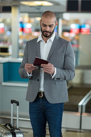 simsearch:400-03938985,k - Businessman with luggage checking his boarding pass at airport terminal Foto de stock - Sin royalties Premium, Código: 6109-08929373
