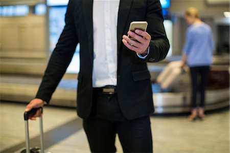 simsearch:400-03938985,k - Mid section of businessman using mobile phone in waiting area at airport terminal Foto de stock - Sin royalties Premium, Código: 6109-08929374