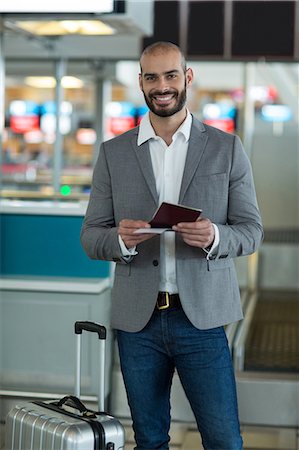 simsearch:400-03938985,k - Portrait of smiling businessman with luggage checking his boarding pass at airport terminal Foto de stock - Sin royalties Premium, Código: 6109-08929375