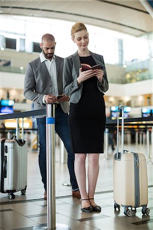 simsearch:400-03938985,k - Businesspeople waiting in queue at a check-in counter with luggage in airport terminal Foto de stock - Sin royalties Premium, Código: 6109-08929390