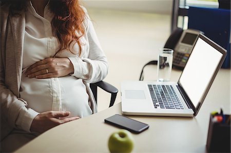 executive women - Mid-section of pregnant businesswoman holding her belly in office Stock Photo - Premium Royalty-Free, Code: 6109-08929326