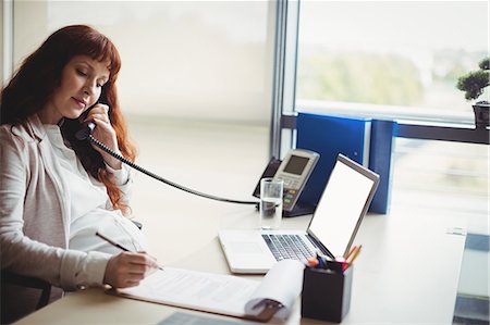 Pregnant businesswoman talking on telephone while working in office Stock Photo - Premium Royalty-Free, Code: 6109-08929329