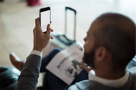 Businessman using mobile phone in waiting area at airport terminal Photographie de stock - Premium Libres de Droits, Code: 6109-08929465