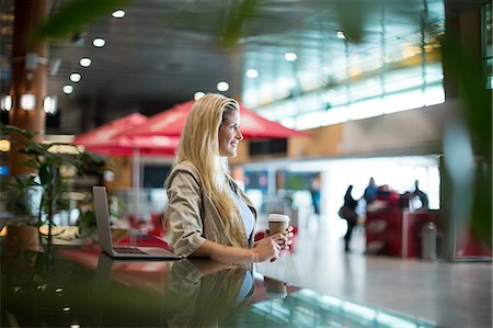 passenger at airport - Smiling woman with coffee standing in waiting area at airport terminal Stock Photo - Premium Royalty-Free, Code: 6109-08929473
