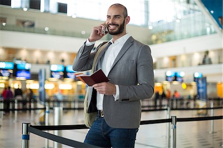 simsearch:400-03938985,k - Smiling businessman holding a boarding pass and talking on mobile phone at airport terminal Foto de stock - Sin royalties Premium, Código: 6109-08929400