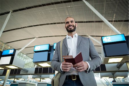 simsearch:400-03938985,k - Smiling businessman holding a boarding pass and passport at airport terminal Foto de stock - Sin royalties Premium, Código: 6109-08929402