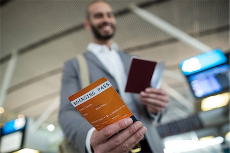simsearch:400-03938985,k - Smiling businessman showing his boarding pass at airport terminal Foto de stock - Sin royalties Premium, Código: 6109-08929404
