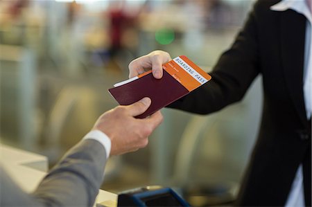 Airline check-in attendant handing passport to commuter at counter in airport terminal Stock Photo - Premium Royalty-Free, Code: 6109-08929416