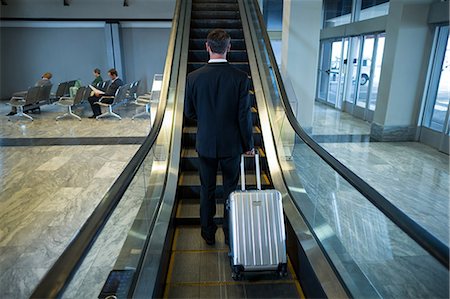 simsearch:400-03938985,k - Rear view of businessman on escalator at airport Foto de stock - Sin royalties Premium, Código: 6109-08929556