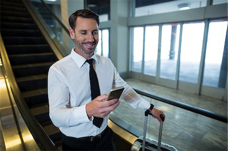 simsearch:400-03938985,k - Businessman on escalator using mobile phone in airport Foto de stock - Sin royalties Premium, Código: 6109-08929560