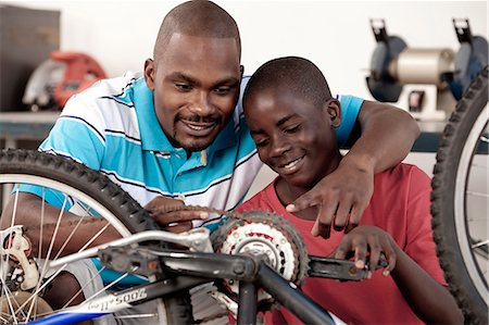 African Father and son working on a bicycle Stock Photo - Premium Royalty-Free, Code: 6110-06702611