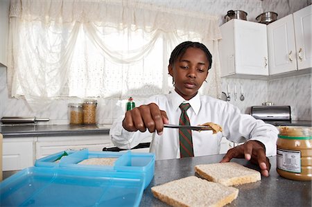 Boy in kitchen spreading peanut butter over bread Stock Photo - Premium Royalty-Free, Code: 6110-07233619