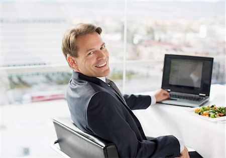 Portrait of smiling businessman with laptop and lunch Stock Photo - Premium Royalty-Free, Code: 6113-06497913