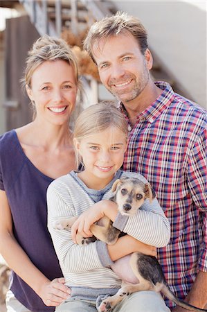 dog and woman and love - Portrait of smiling family holding puppy Stock Photo - Premium Royalty-Free, Code: 6113-06498052