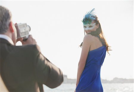 Man filming woman with mask at waterfront in Venice Stock Photo - Premium Royalty-Free, Code: 6113-06498128