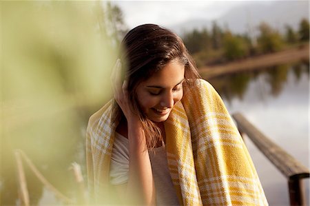 Smiling woman wrapped in blanket at lakeside Stock Photo - Premium Royalty-Free, Code: 6113-06498475