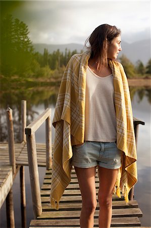 Woman wrapped in blanket standing on dock over lake Stock Photo - Premium Royalty-Free, Code: 6113-06498555
