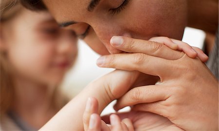 Close up of mother kissing daughter's hand Stock Photo - Premium Royalty-Free, Code: 6113-06498577