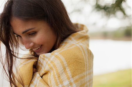 Close up of smiling woman wrapped in blanket at lakeside Stock Photo - Premium Royalty-Free, Code: 6113-06498509
