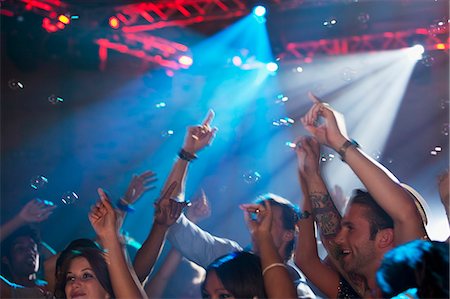 Enthusiastic crowd with arms raised on dance floor of nightclub Foto de stock - Sin royalties Premium, Código: 6113-06498643